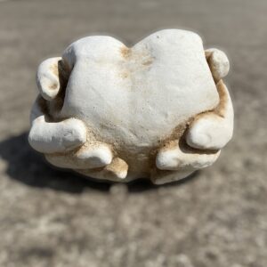 Statua cuore nelle mani,scultura in cemento e pietra, cuore d’amore, mano nella mano.
